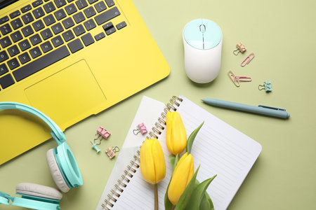 Composition with laptop, headphones, stationery and tulip flowers on color background