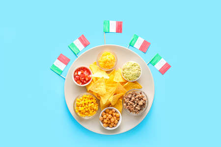 Plate with Mexican traditional food and flags on blue background