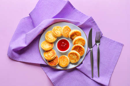 Plate with cottage cheese pancakes and jam on color backgroundの写真素材