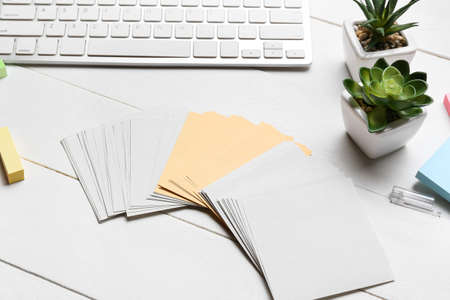 Blank sticky notes, houseplants and keyboard on white wooden tableの写真素材