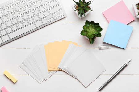 Blank sticky notes, houseplants, pen and keyboard on white wooden backgroundの写真素材