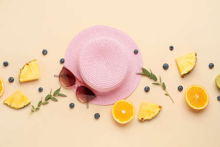 Composition with stylish hat, sunglasses and fruits on color background