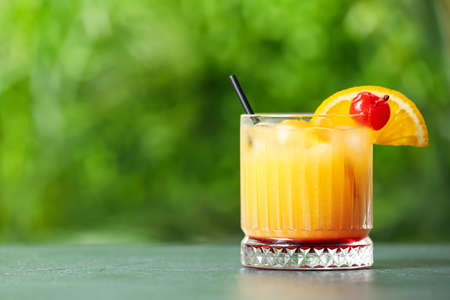Glass of tasty Tequila Sunrise cocktail on table outdoorsの写真素材