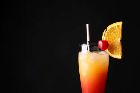 Glass of tasty Tequila Sunrise cocktail on dark background, closeupの写真素材