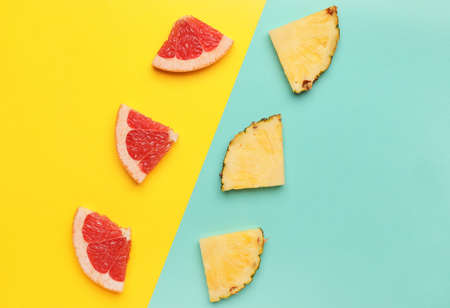 Slices of ripe grapefruit and pineapple on color background