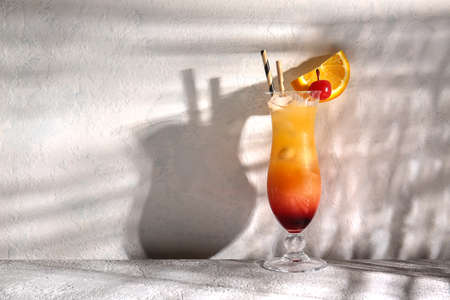 Glass of tasty Tequila Sunrise cocktail on light backgroundの写真素材