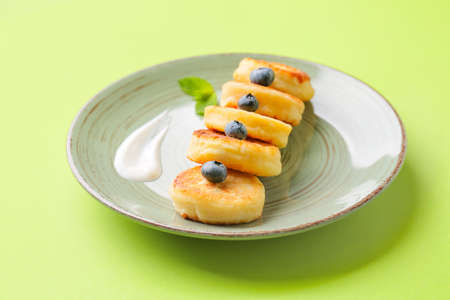 Plate with cottage cheese pancakes and blueberry on color background, closeupの写真素材