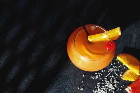 Glass of tasty Tequila Sunrise cocktail on dark background