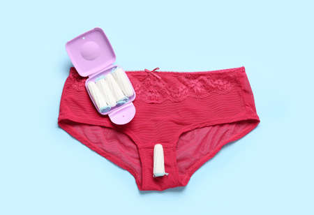 Tampons storage box and female panties on blue background, top view