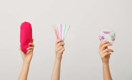 Female hands with school supplies on gray background