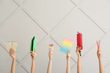 Many different hands with school supplies on gray wall backgroundの写真素材