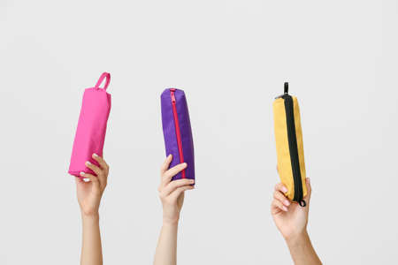 Female hands with pencil cases on gray background