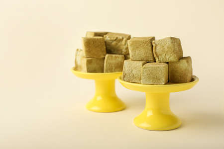 Stands with tasty hojicha marshmallows on color background