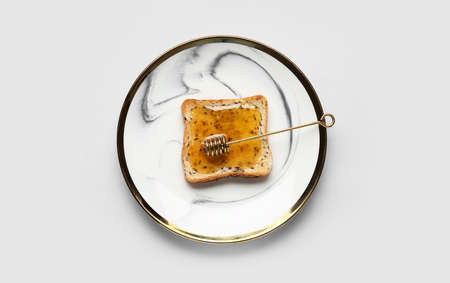 Plate with tasty toasted bread with honey on light background