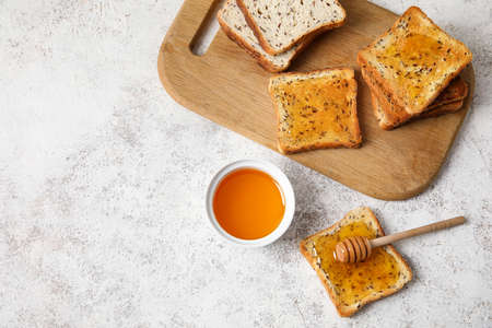 Delicious toasted bread with honey on light backgroundの写真素材