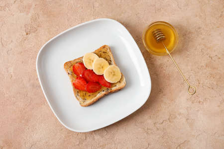 Plate of delicious toasted bread with honey and fruits on beige backgroundの写真素材