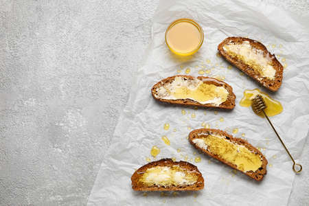 Delicious toasted bread with honey and butter on light background