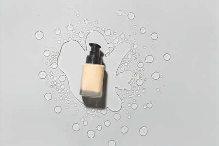 Bottle of makeup foundation in water on gray backgroundの写真素材