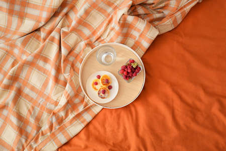 Tray with tasty breakfast on bed with plaid