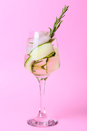Glass of cold gin tonic and cucumber slices on color backgroundの写真素材