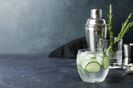 Glass of cold gin tonic and cucumber slices on dark background