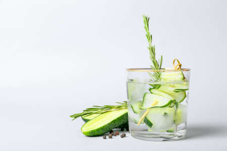 Glass of cold gin tonic and cucumber slices on light backgroundの写真素材