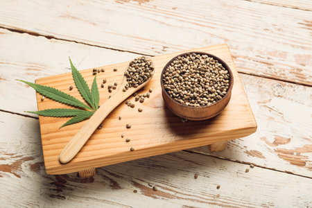 Bowl and spoon with hemp seeds on white wooden backgroundの写真素材