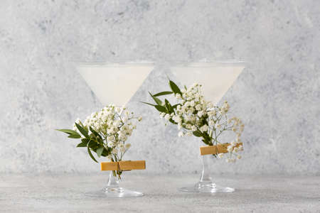 Glasses with tasty cocktail and beautiful gypsophila flowers on light backgroundの写真素材