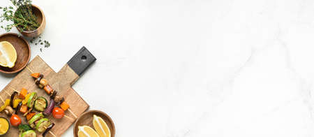 Board with tasty vegetable skewers and lemon on light background with space for text
