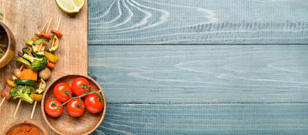 Board with tasty vegetable skewers on wooden background with space for textの写真素材