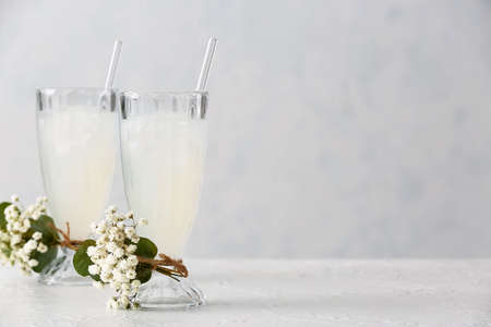 Glasses with tasty cocktail and beautiful gypsophila flowers on light backgroundの写真素材