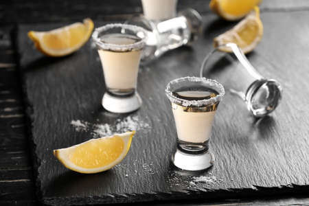 Shots of tasty mexican tequila with lemon on table