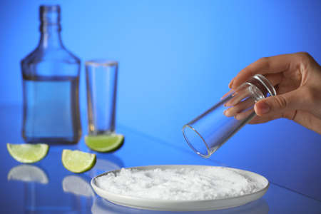 Woman preparing shot for tasty mexican tequila on color backgroundの写真素材