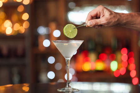 Male bartender making tasty margarita cocktail on table in bar