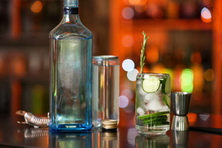 Glass of cold cucumber gin tonic and ingredients on table in barの写真素材
