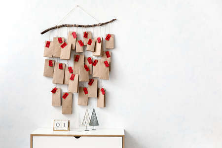 Advent calendar hanging on white wall near chest of drawers with decorの写真素材