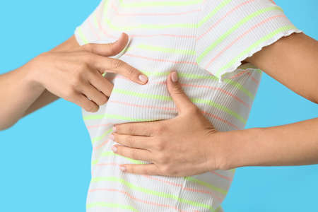 Young woman feeling discomfort in her breast on color background. cancer awareness conceptの写真素材