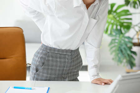 Young woman feeling back pain in officeの写真素材