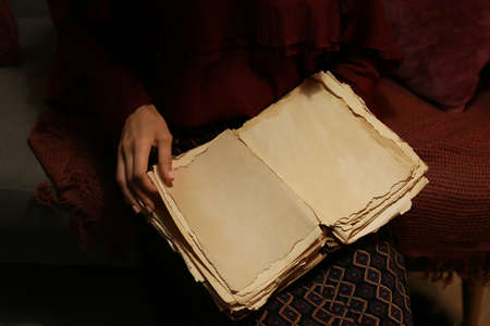 Woman reading old book at home, closeup