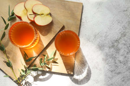 Glasses of apple juice on light backgroundの写真素材
