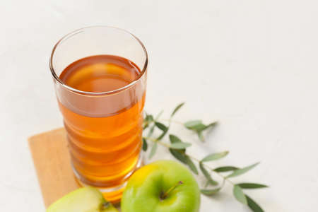 Glass of apple juice and fresh fruits on light background