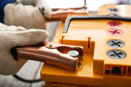 Man testing car battery on wooden background, closeupの写真素材