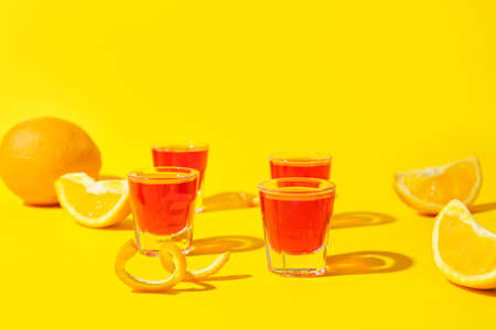 Shot cocktails and oranges on color background