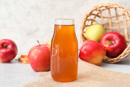 Bottle of apple juice on light background