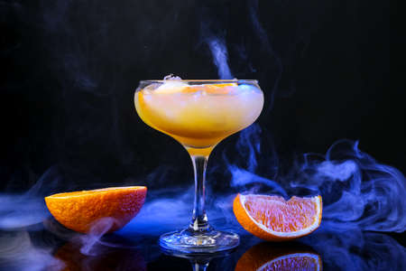 Glass of tasty orange margarita cocktail on dark background