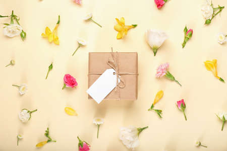 Beautiful spring composition with flowers, blank tag and gift box on yellow background
