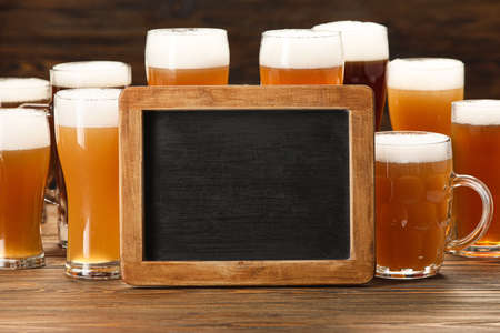 Glasses of cold beer and blank chalkboard on table. Oktoberfest celebrationの写真素材