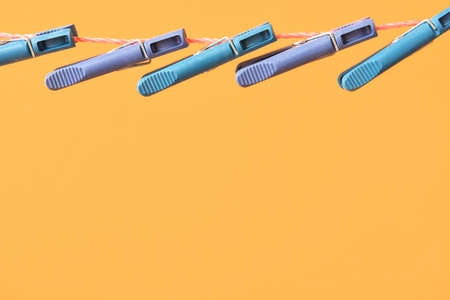 Many plastic clothespins hanging on rope against color background, closeupの写真素材