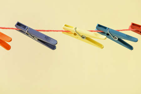 Different clothespins hanging on laundry line against color background, closeup