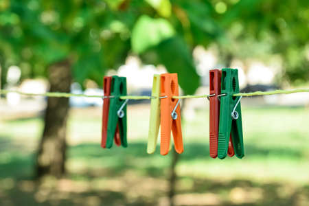 Colorful plastic clothespins hanging on rope outdoorsの写真素材